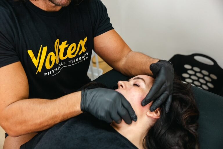 Physical therapist examining a client’s jaw and neck at Voltex in Austin